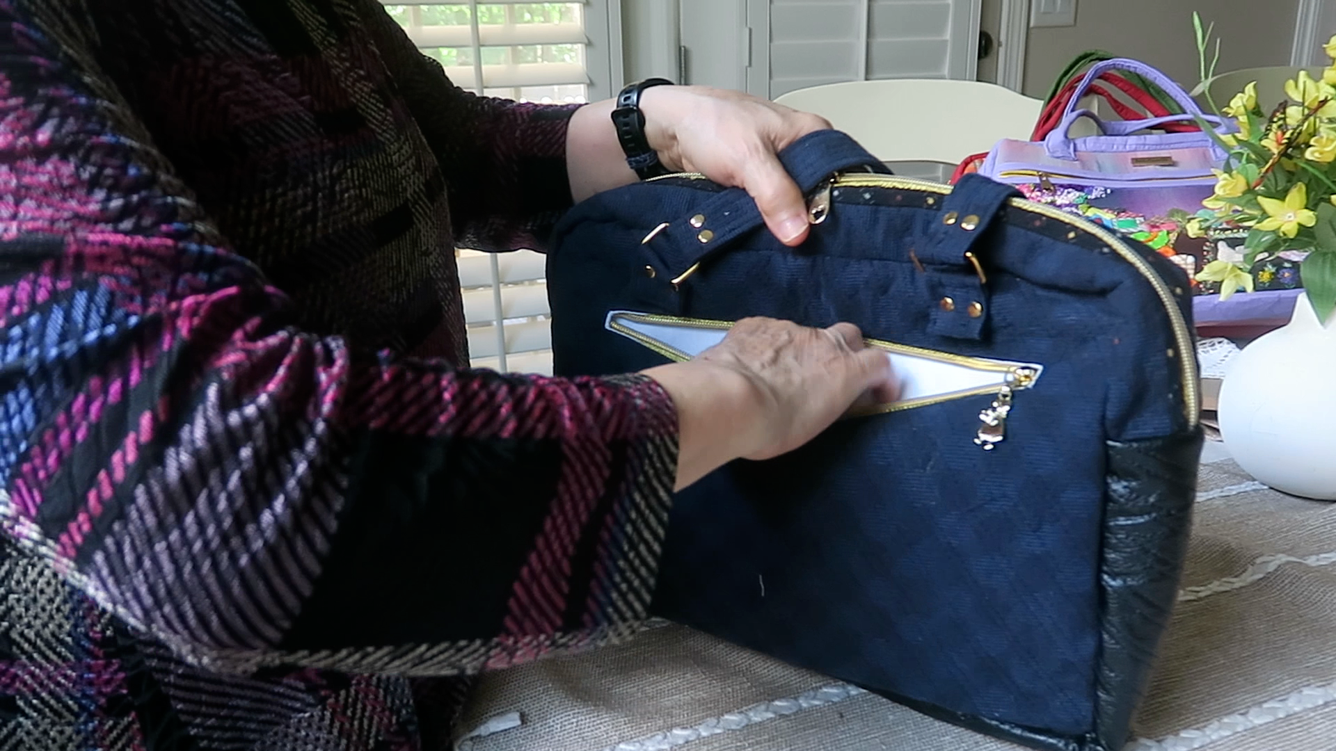 Handmade floral shoulder bag showing spacious back zipper storage pocket and appliqué design details.