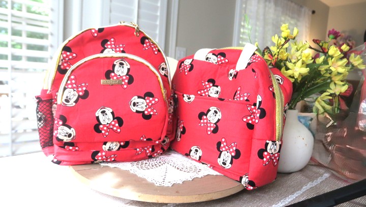 Handmade red matching backpack and shoulder bag set displayed together on a table.