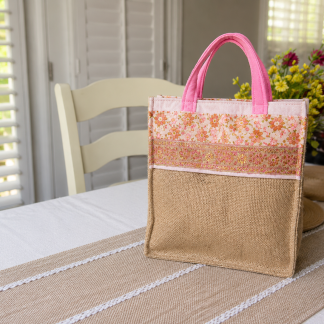 Handmade burlap shopping tote with floral fabric accents and pink carry handles