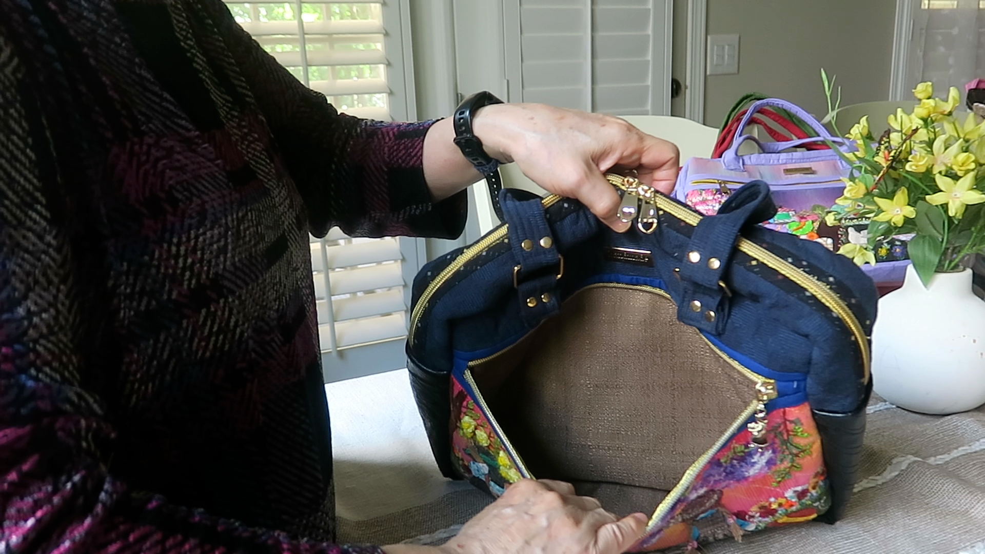 Handmade floral shoulder bag showing spacious front zipper storage pocket and appliqué design details.