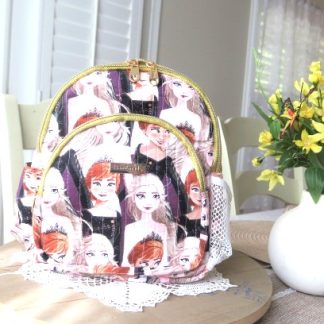 Handmade beautiful girls mini backpack with colorful character-inspired fabric, gold zipper accents, and boutique-style design displayed beside flowers indoors.