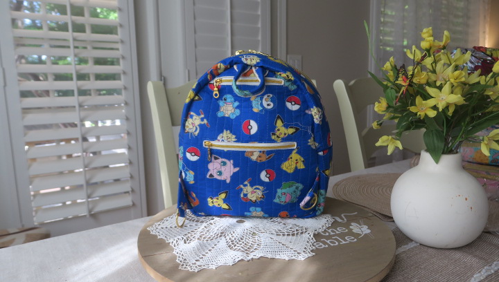 Handmade blue character-inspired mini backpack with quilted fabric, zipper compartments, and boutique-style design.
