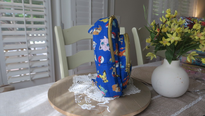 Handmade blue character-inspired mini backpack with quilted fabric, zipper compartments, and boutique-style design.