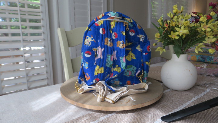 Handmade blue character-inspired mini backpack with quilted fabric, zipper compartments, and boutique-style design.