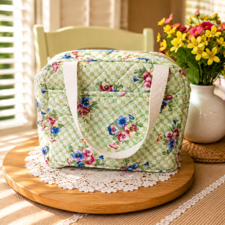 Handmade green floral quilted cotton lunch tote with soft handles displayed on rustic wooden table