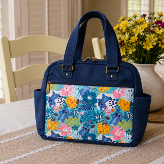 Handmade quilted shoulder bag with floral fabric, front zipper pocket, and double zipper top closure