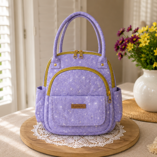 Handmade lavender floral boutique backpack with elegant floral-pattern fabric and carrying handles displayed on a wooden table beside decorative flowers indoors.