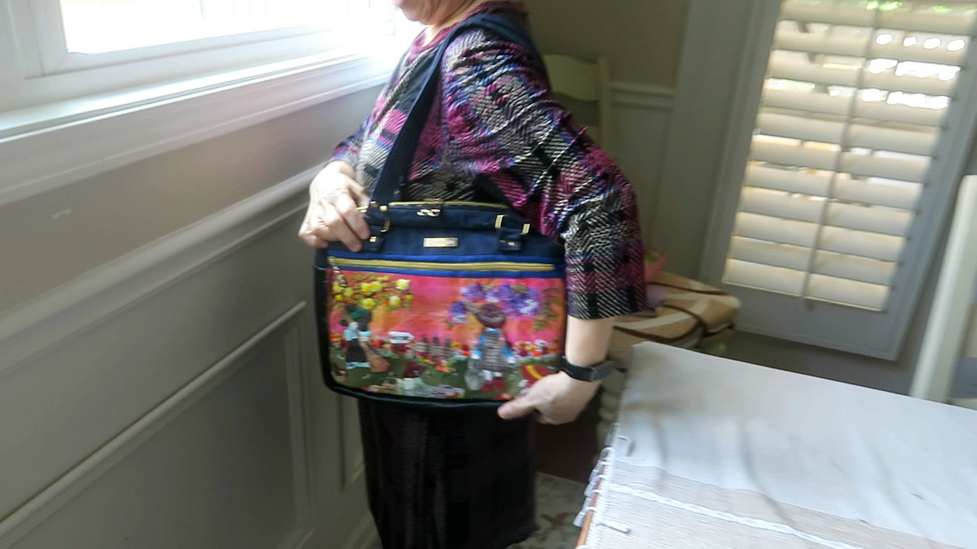 Handmade floral iPad and notebook shoulder bag displayed worn over the shoulder showing comfortable strap length and everyday carry size.