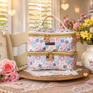 Handmade floral double stacker lunch tote with two zippered compartments displayed on a table beside flowers in natural light.